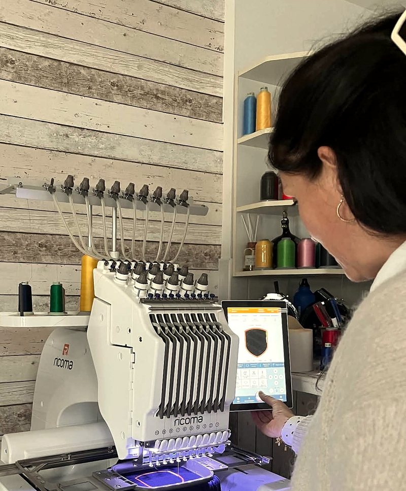 Aurélie dans son atelier, devant sa brodeuse en train de lancer une broderie