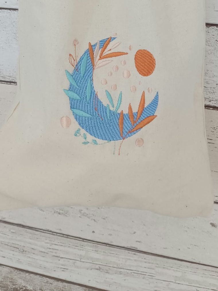 Pochon en coton naturel brodé d'une lune bleue et de feuillages orangés